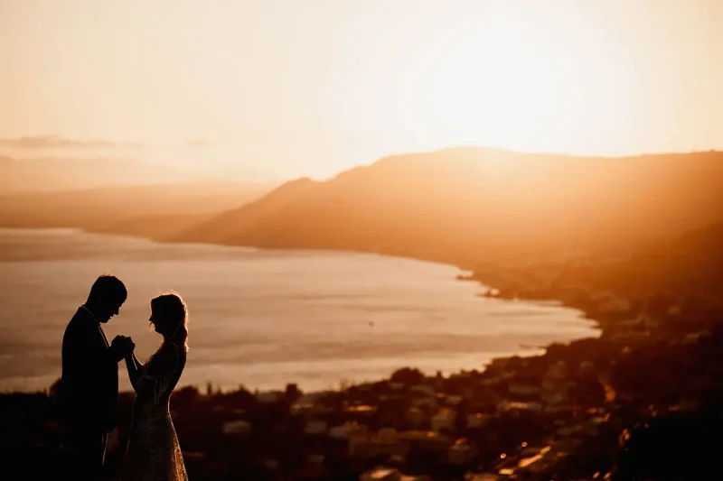Destination wedding silhouette photo of a bride and groom above the town of pefkos in rhodes greece by destination wedding photographer Oben Studio®
